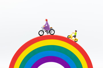 Miniature people : Mom and kids cycling on the rainbow. Image use for to be good model, family concept.