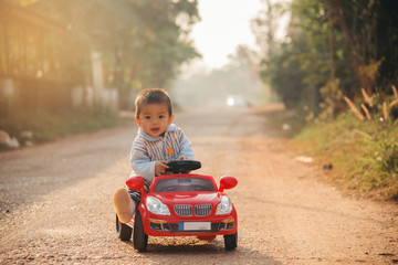 Little boy driving big toy car ,Child enjoying warm summer day in sunrise morning