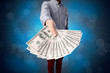 © ra2 studio - Young businessman holding large amount of bills with shiny blue background