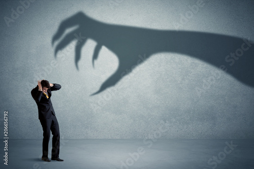 Fotografía Business person afraid of a big monster claw shadow concept on background