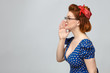 Sideways profile of attractive stylish young lady in vintage clothes calling someone, whispering secret or gossip, keeping hand at her mouth, posing at blank wall with copy space for your content
