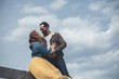 © Yakobchuk Olena - Wonderful day for being together. Happy romantic couple cuddling with love and smiling. Woman is sitting on wooden beam and looking into male eyes with fondness