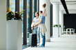 © pressmaster - Family of father, mother and little girl looking outdoors through transparent door inside airport