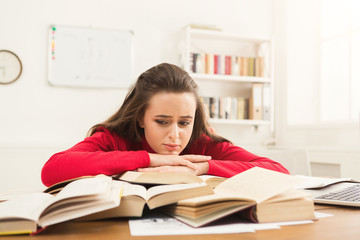 Student girl studying at table full of books