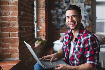 Cheerful man using computer at home.