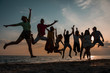 © ManuPadilla - Silhouettes of group of people in a jump at sunset. nine young men and women depicted in a jump against the evening sky and the beach. Friends and holiday concept