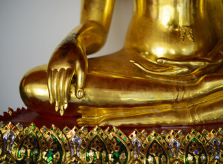 Close up view of the low hand golden buddha statue sitting meditation with copy space and sunlight