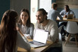 © fizkes - Smiling couple meeting realtor or mortgage insurance broker in cafe, financial consultant making offer to happy clients with laptop in public place, millennial friends having fun in coffee shop