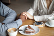 © fizkes - Interracial couple holding hands sit at cafe table, african black man and white woman in love enjoy date in coffee house concept, romantic biracial lovers meet in public place together, close up view