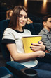 © Nomad_Soul - Woman eats popcorn while watching movie in cinema