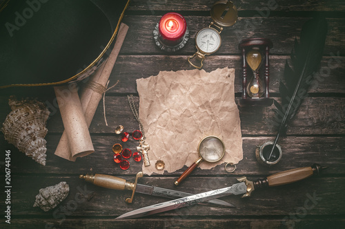 Fotomural Pirate captain table with crumpled paper page with copy space for treasure map, golden compass, sand watch, scrolls,gemstones, seashell and dagger