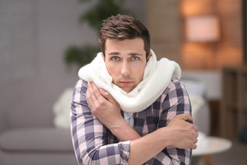 Wall Mural - Sad young man suffering from cold on blurred background