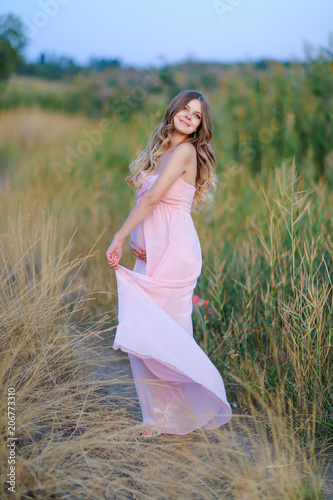 Fotografía Pregnant young female person wearing pink dress standing in steppe background