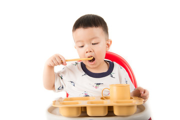 ASian baby boy sitting on the chair while eat and drink his meal time