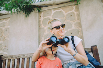 Young woman with her cute little son sightseeing with binoculars in Dubai, UAE