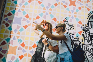 Two young happy women against bright wall in Dubai, UAE