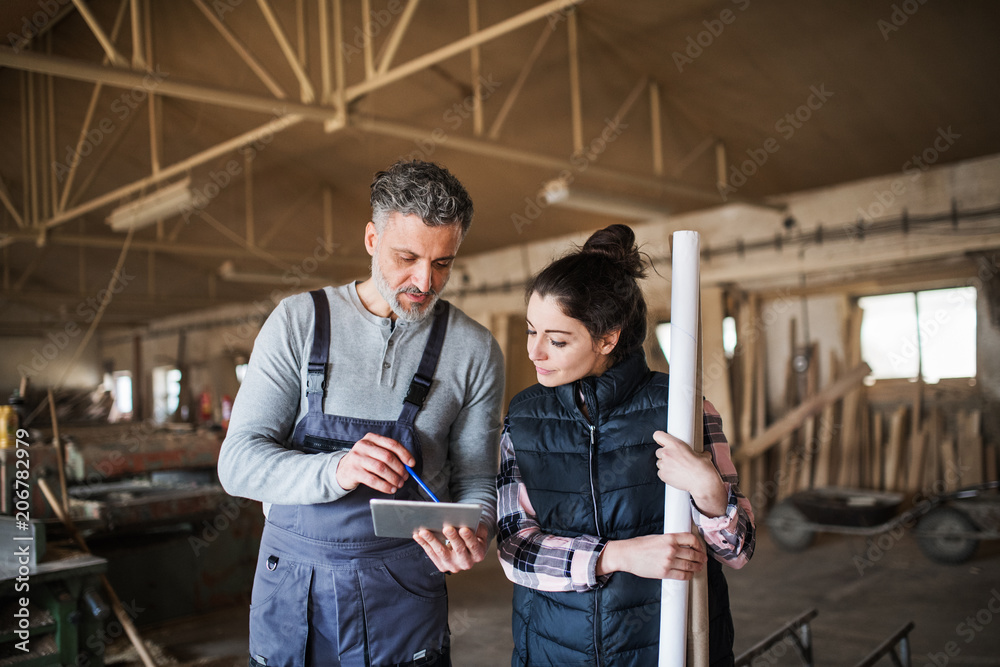 Man and woman workers with tablet in the carpentry workshop. - obrazy, fototapety, plakaty 