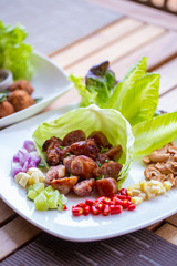 Wall Mural - A dish of Thai style fermented sausage with side herbs, chili, lime, ginger, cashew nut. garlic and shallot on dining table.