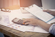 © chaiya - A businessman analyzing investment charts at his workplace and using his laptop and touch calculator.