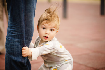 Wall Mural - Concept: family values. Portrait of adorable innocent funny brown-eyed baby playing at outdoor playground.