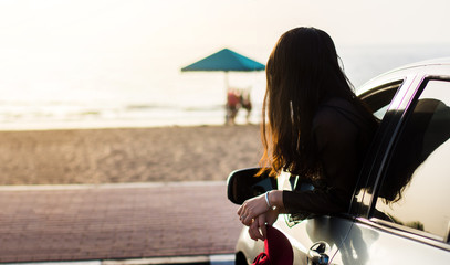 Wall Mural - Girl enjoying beach sunset out of the car window