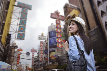 young asian woman traveler with a backpack on her shoulder and travel hat walking on footpath over c