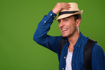 Young handsome Hispanic tourist man against green background