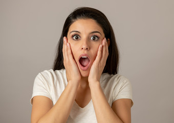 Young attractive woman with a surprised and shocked face, eyes and mouth wide open.