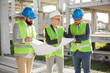 © Ivan - Mixed group of engineers or business partners at construction site, working together on building's blueprint. Architecture and teamwork concept.