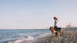Happy young woman have a rest with her German shepherd dog outdoor on the beach
