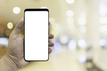 Poster - Hand holding smartphone with blur interior in shopping mall.