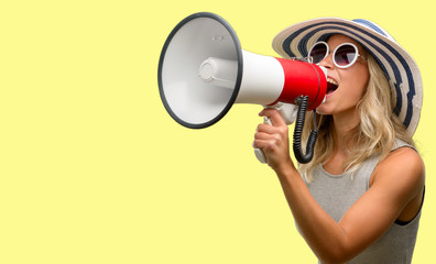 Young woman wearing sunglasses and summer hat communicates shouting loud holding a megaphone, expressing success and positive concept, idea for marketing or sales