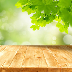Wall Mural - wooden table with copy space for products and blurred green background and with tree leaves and bran