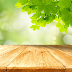 Wall Mural - wooden table top with copy space for products and blurred green background and with tree leaves and 