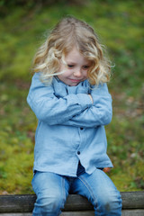 Canvas Print - Angry child with long blond hair crossing his arms