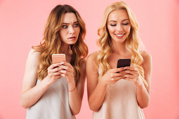 Wall Mural - Two young pretty women in pajamas using smartphones