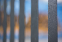 An Abstract Style Shot Of Black Painted Palisade Fencing With Yellow And Blue Graffiti In The Background