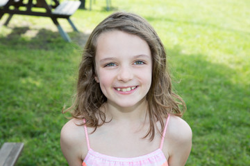 Outdoor close up portrait of a cute young child girl smiling