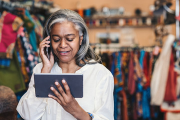 Wall Mural - Clothing shop owner using a digital tablet and cellphone