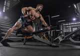 Handsome young fit muscular caucasian man of model appearance workout training in the gym gaining weight pumping up muscle and poses fitness and bodybuilding sport nutrition concept