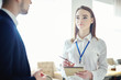 © Comeback Images - Young businesswoman with accreditation badge around her neck talking to unrecognizable male colleague. Female professional networking at business conference