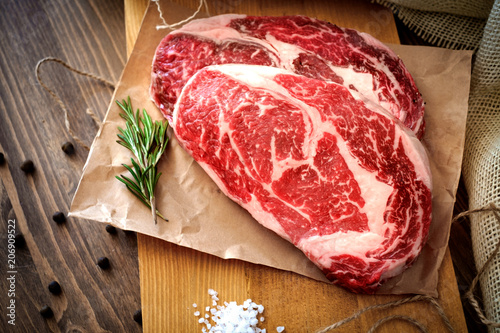 Fotografía Two raw rib eye steak on a wooden Board on a table prepared for the grill