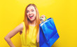© Tierney - Young woman holding a shopping bag on a yellow background
