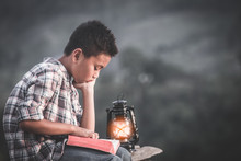 Boy Reading Bible With Light Of Oil Lamp, Christian Concept.