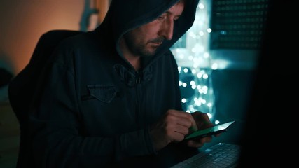 Wall Mural - Computer hacker using smartphone in dark interior