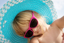 Portrait Of A Little Girl In Pink Sunglasses And Blue Hat.