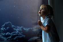 The Child Looks Out The Window Into The Night Sky