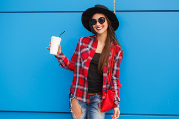 Wall Mural - Portrait of beauty fashion smiling woman with coffee in sunglasses on blue background. Outdoor