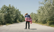 Man With Hat And A American Flag On A Lonely Road