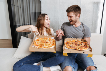 Poster - Cheerful young couple holding boxes with pizza